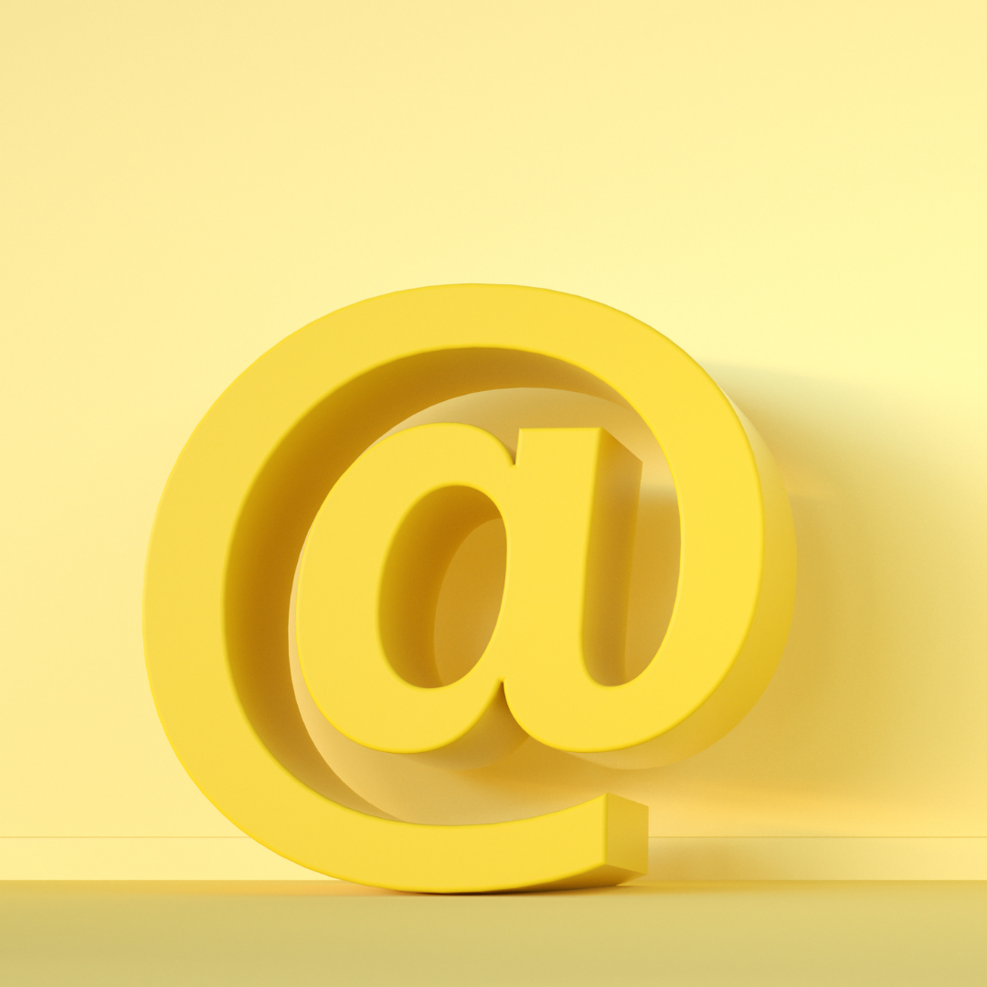 Email at symbol. 3D yellow shape against a lighter yellow wall. Made with Canva.