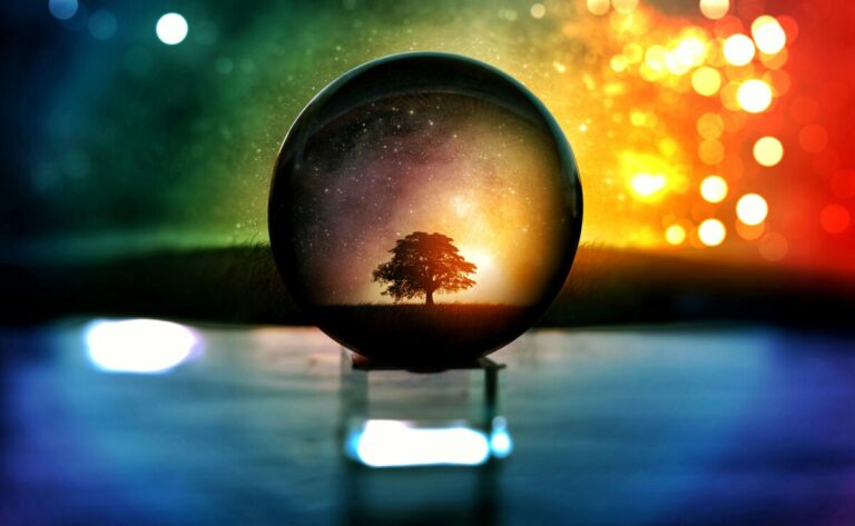 Crystal ball, against a rainbow of colours, with a tree visible within it.