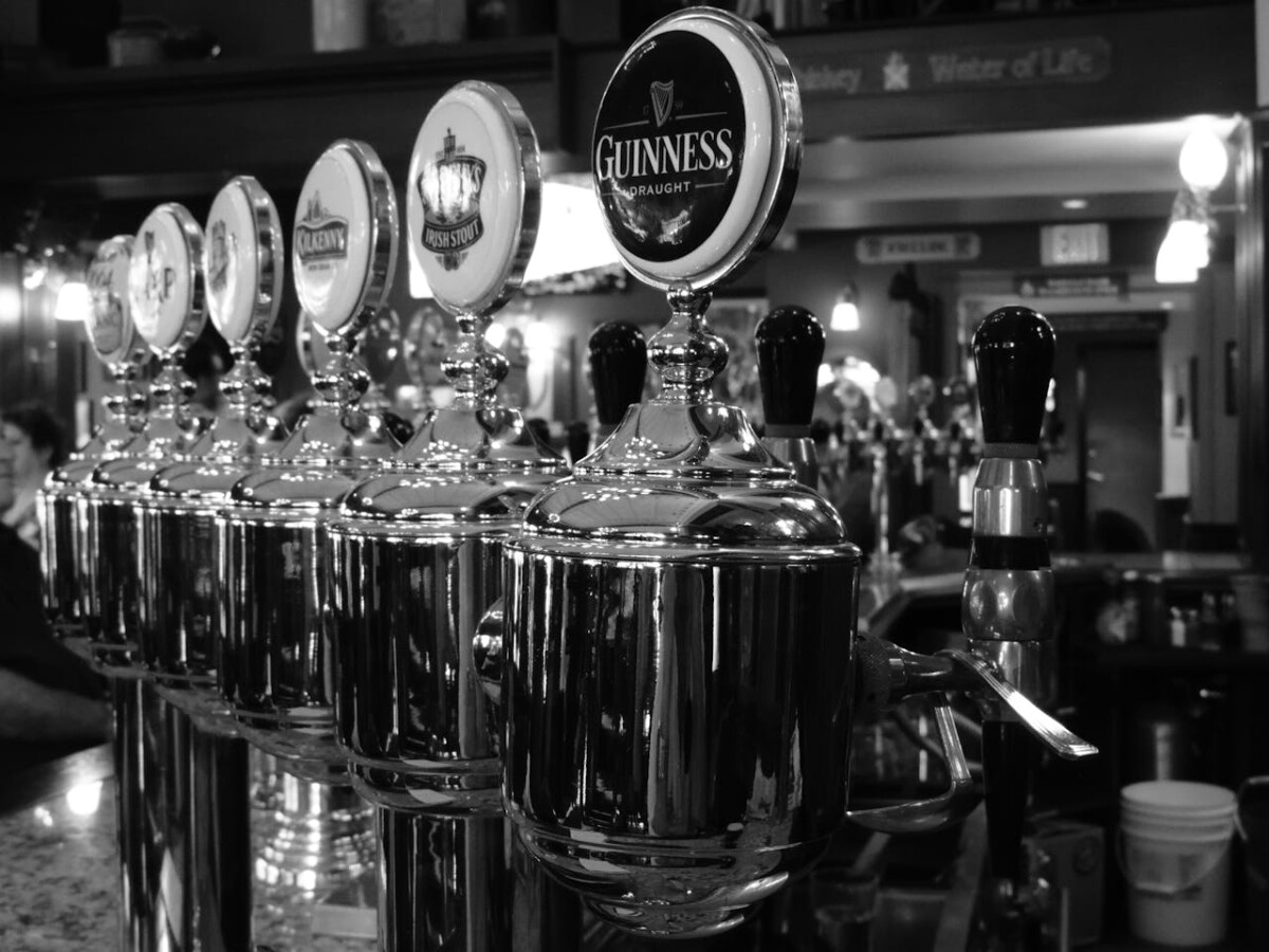 Guinness and other beers on a bar in a pub.