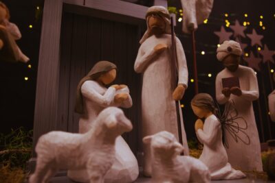 Carved wooden Christmas nativity scene figures, with sheep at the foreground.