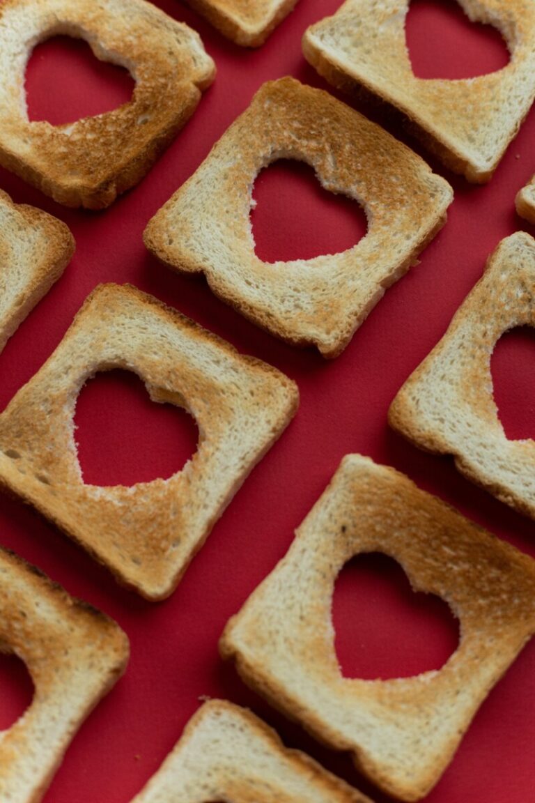 Slices of toast in rows with heart shapes cut from them.