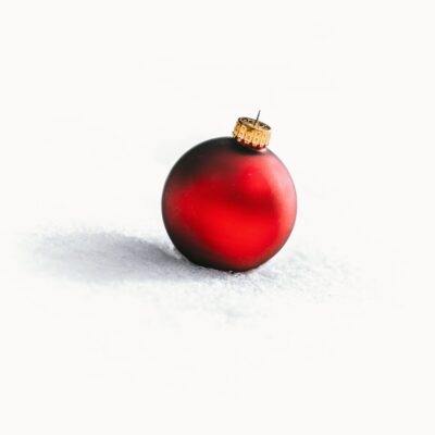 Red Christmas bauble on a white, snowy background.