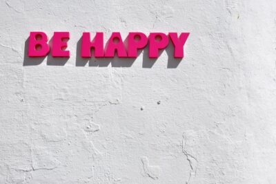'Be Happy' sign in pink on a white wall in Cordoba - image: Unsplash