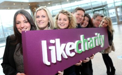 LikeCharity - purple signboard with the logo held up by people in a row