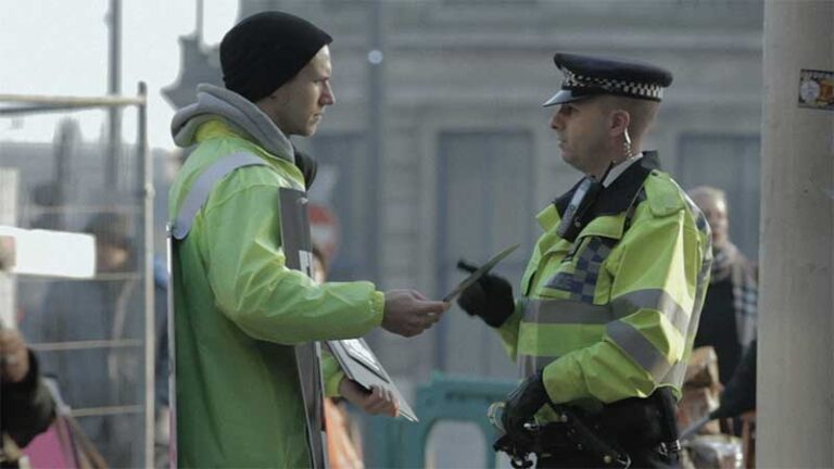 A Fuck the Poor campaigner is spoken to by a Metropolitan police officer.