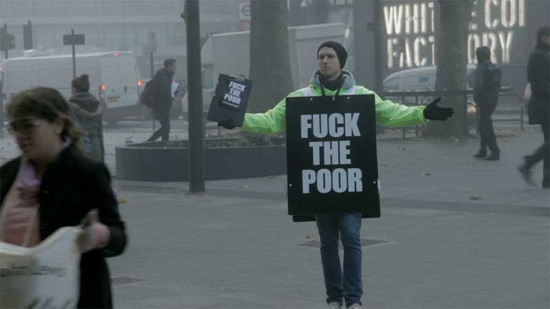 Fuck the Poor campaigner with large sandwich board and hi-viz jacket on the streets of London