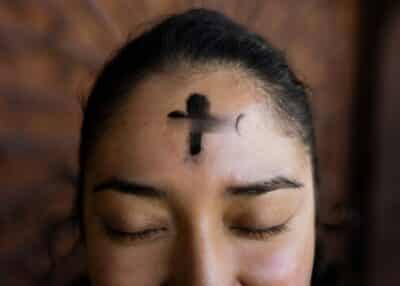 Cross of ashes on a women's forehead, marking Lent