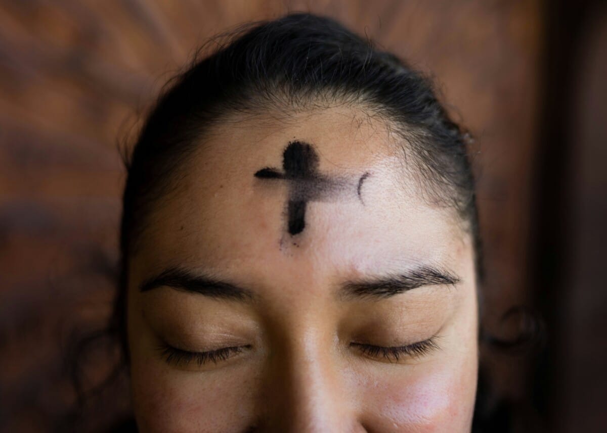 Cross of ashes on a women's forehead, marking Lent