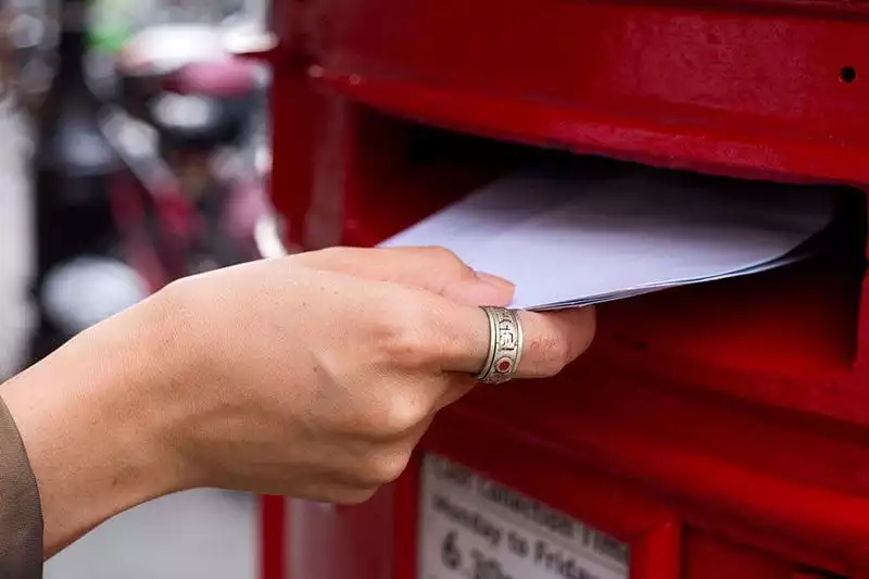 Posting a letter in a red pillarbox