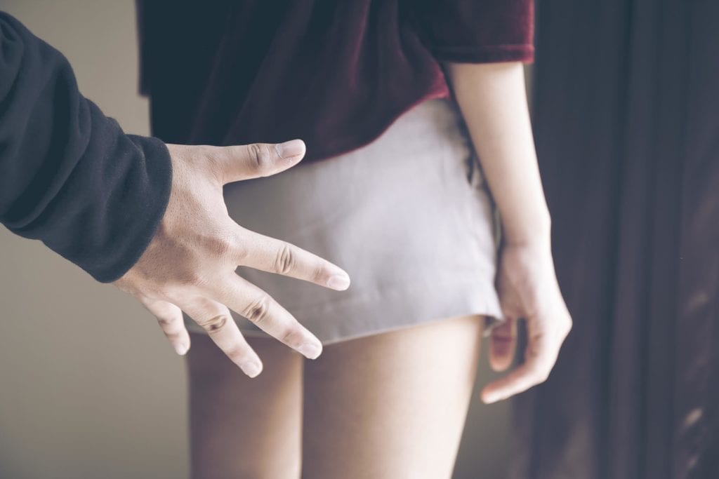 Male hand about to touch a woman from behind