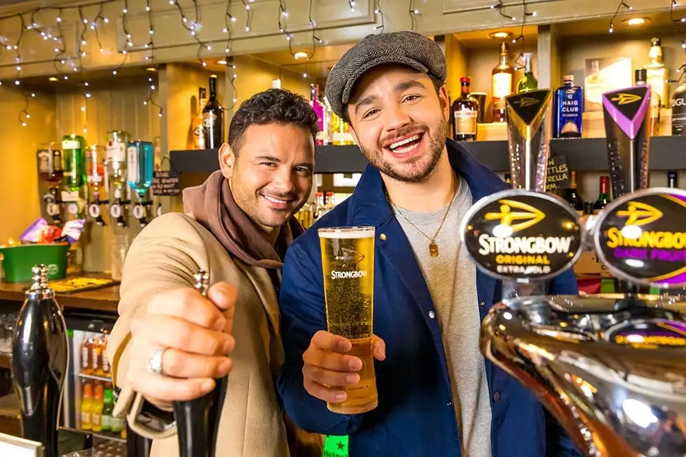Ryan and Adam Thomas raise their glasses to Brewing Good Cheer from behind the bar
