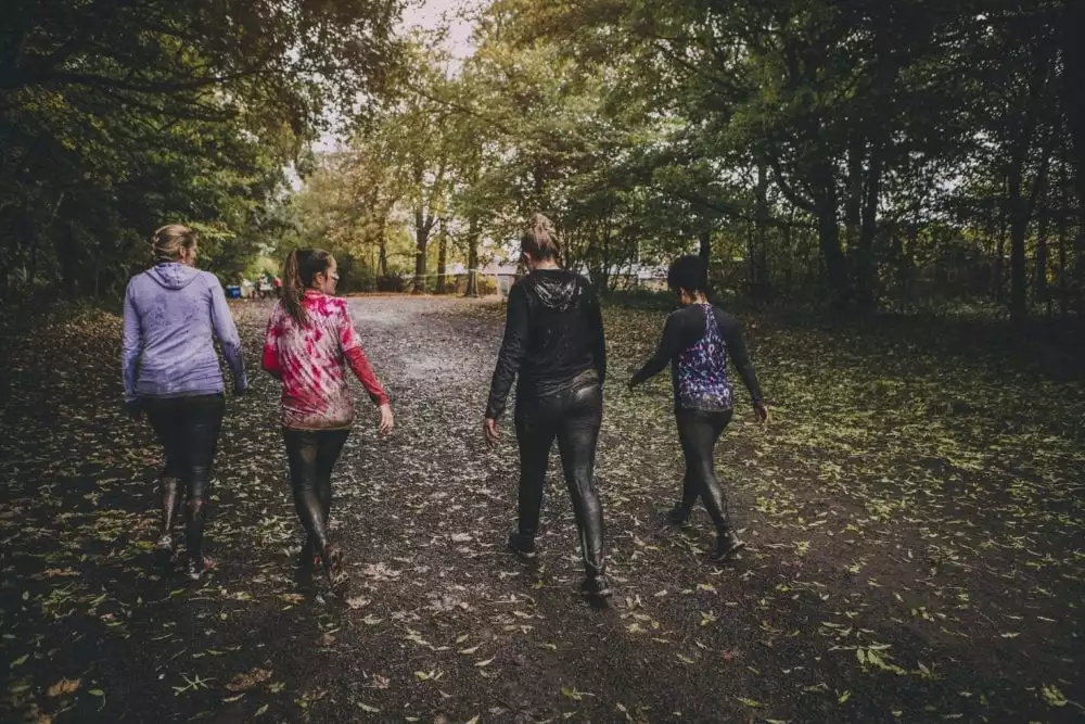 Four women taking part in a charity challenge event in a wood.