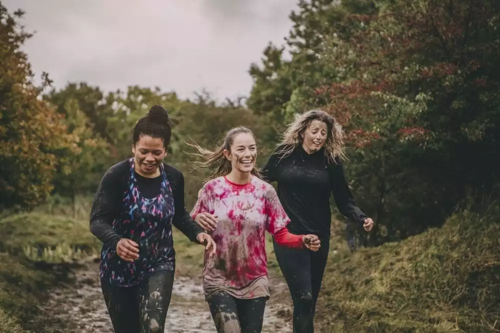 Three women are running through the woods as part of a charity obstacle race.