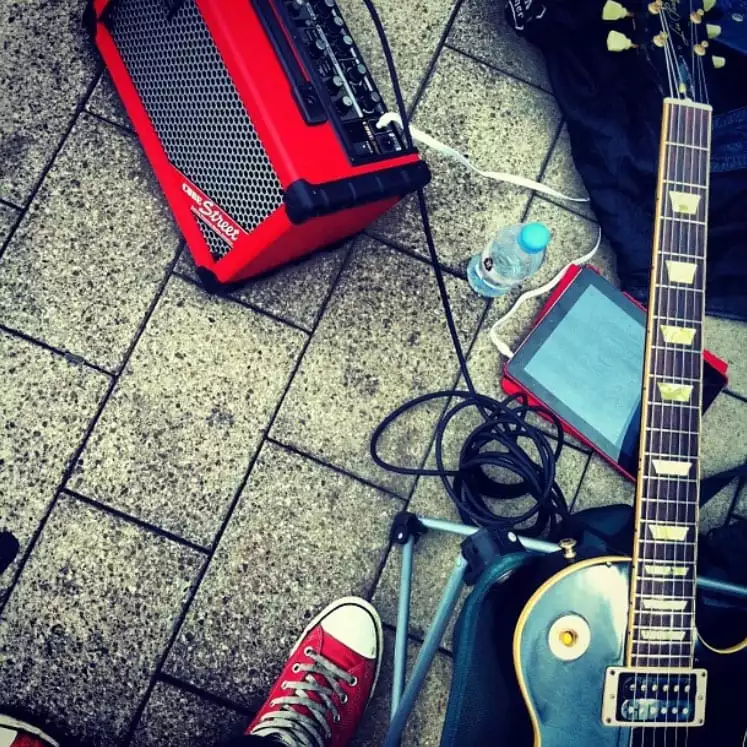 Guitar, amp and other busking equipment on the pavement