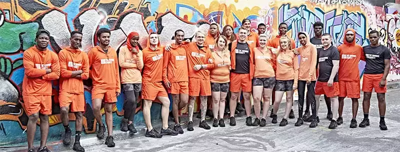 Running Charity runners in orange running gear standing in front of a colourful wall of graffiti
