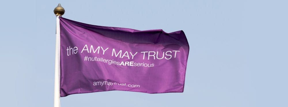 Amy May Trust purple flag in the breeze, with hashtag #NutAllergiesAREserious
