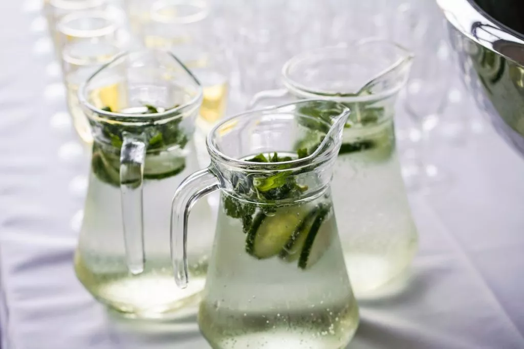 Three glass jugs of water on a table with glasses and a white tablecloth - photo: Unsplash