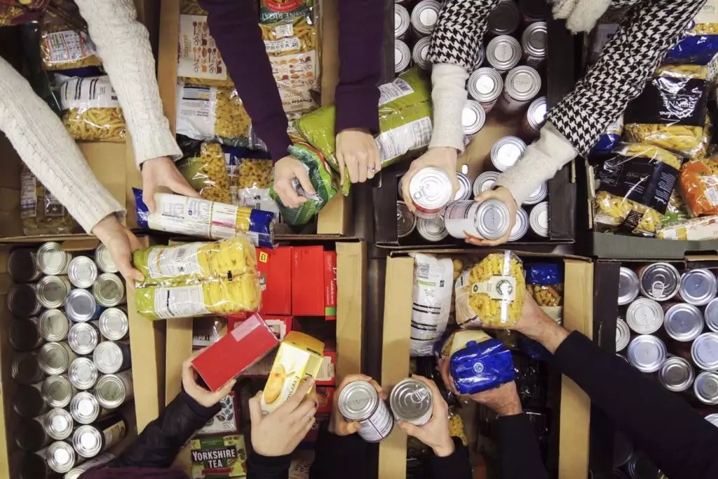 Volunteers sort tins in a foodbank warehouse