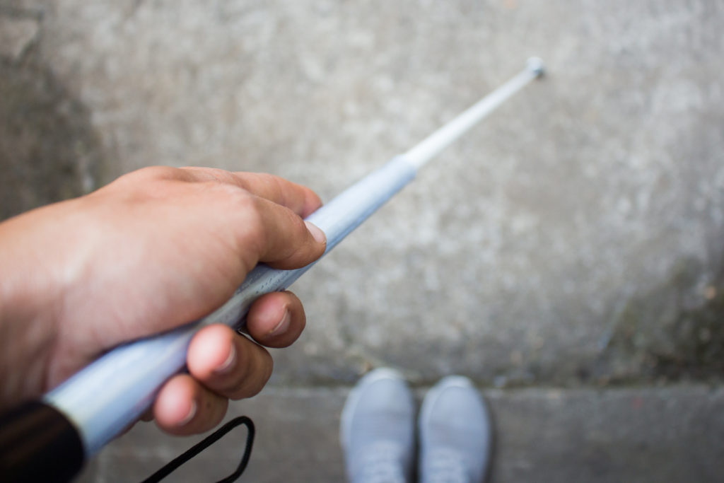 Looking down at a hand holding a white can signifying sight loss or disability