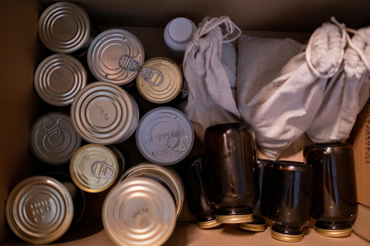Tinned food and food in jars in a cardboard box.