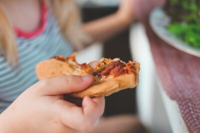Pizza slice in child's hand. Photo: Unsplash.com