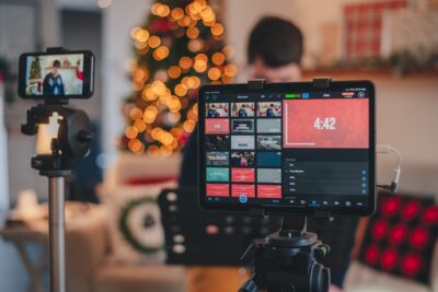 Christmas video being filmed in a living room with a Christmas tree with lights on in the background, blurred.