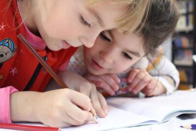 Two children working on an exercise book. Photo: Pexels.com