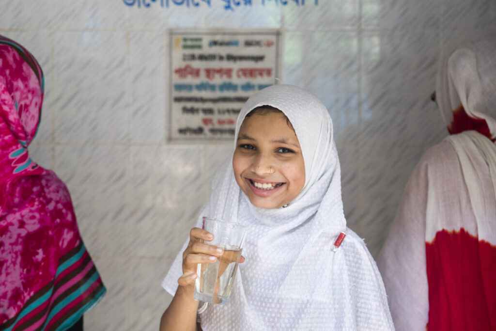 Smiling girl with a glass of clean water