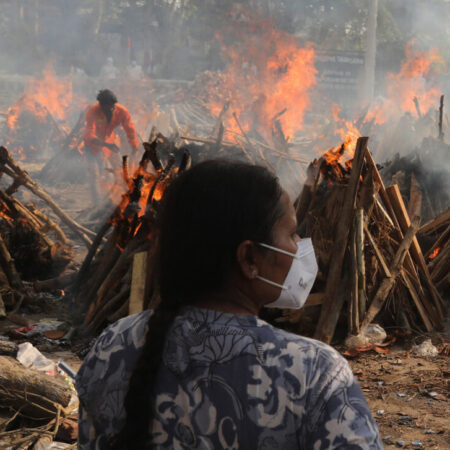 A family member looks on as several funeral pyres of patients who died of Covid-19 burn during the mass cremation at Ghazipur cremation ground in New Delhi, India. Photo: Naveen Sharma/SOPA Images/LightRocket via Getty Images