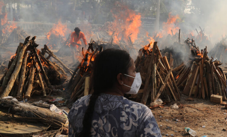 A family member looks on as several funeral pyres of patients who died of Covid-19 burn during the mass cremation at Ghazipur cremation ground in New Delhi, India. Photo: Naveen Sharma/SOPA Images/LightRocket via Getty Images