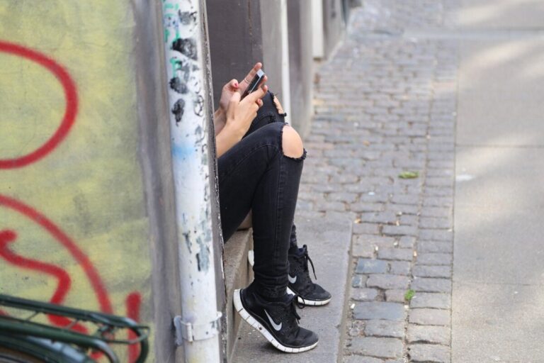 Teenage girl in black jeans on phone - photo: Pixabay