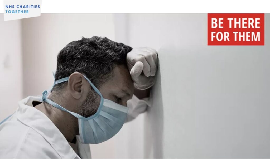 Be There for Them campaign image showing medic leaning against a wall, exhausted. Photo: NHS Charities Together