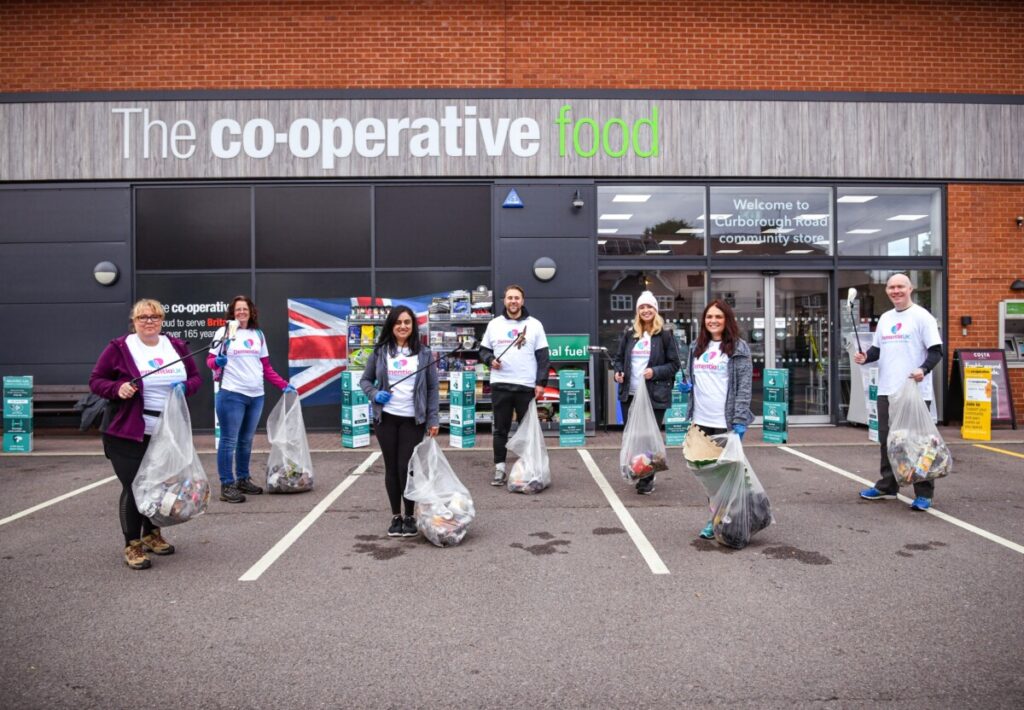 A group of smiling litter pickers outside a Co-op store