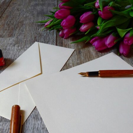 a fountain pen, with a bottle of ink, writing paper, & tulips by Bruno /Germany from Pixabay