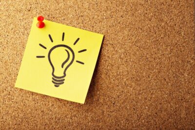 A yellow post-it with a lightbulb drawing on it, on a cork notice board by Gino Crescoli from Pixabay