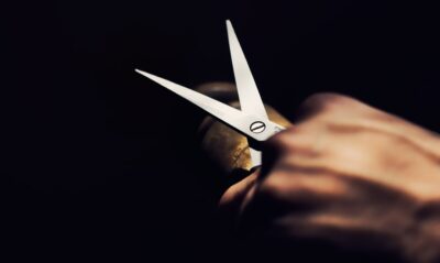 A hand holding open scissors. Photo: Pixabay