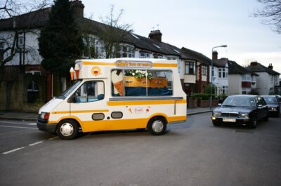 Hearse inside an ice cream van, followed by mourners in cars