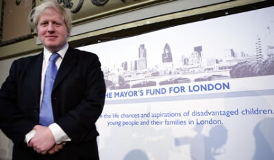 Boris Johnston standing beside a poster for The Mayor's Fund for London