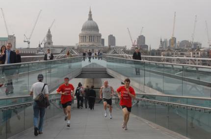 Runners for Crisis run up onto the Millennium Bridge across the Thames in London