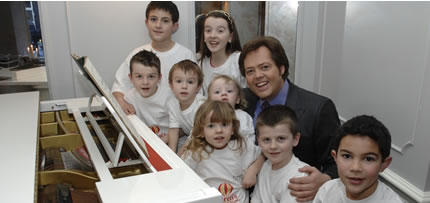 Jimmy Osmond at the piano surrounded by children