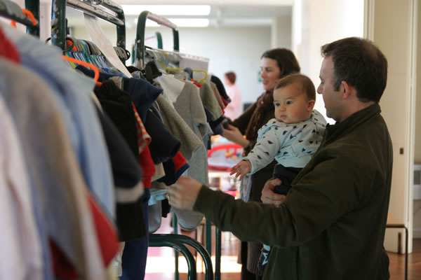 Man and baby looking at children's clothes on a rack at a NCT Nearly New Sale