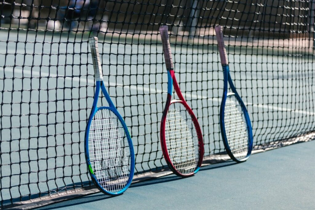 Three tennis rackets against a net. Photo: RODNAE Productions on Pexels