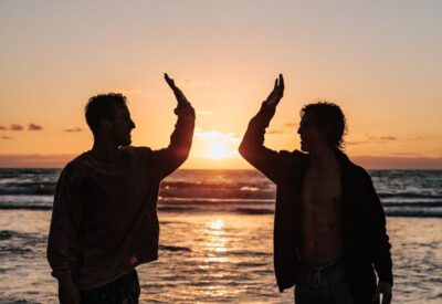 two men high fiving on a beach. Photo: Unsplash.com