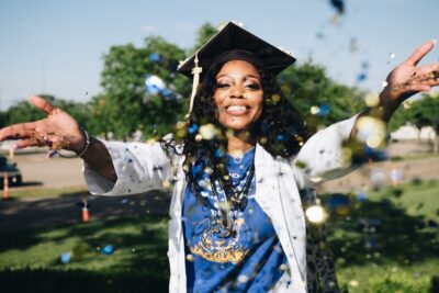 Woman with mortarboard celebrates graduating by throwing glitter - image: pexels.com