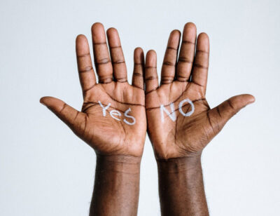 Two black hands, open and touching, one with 'yes' and the other with 'no' drawn on them in white