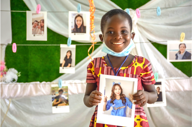 A child supported by World Vision holds the photo of the sponsor she has chosen