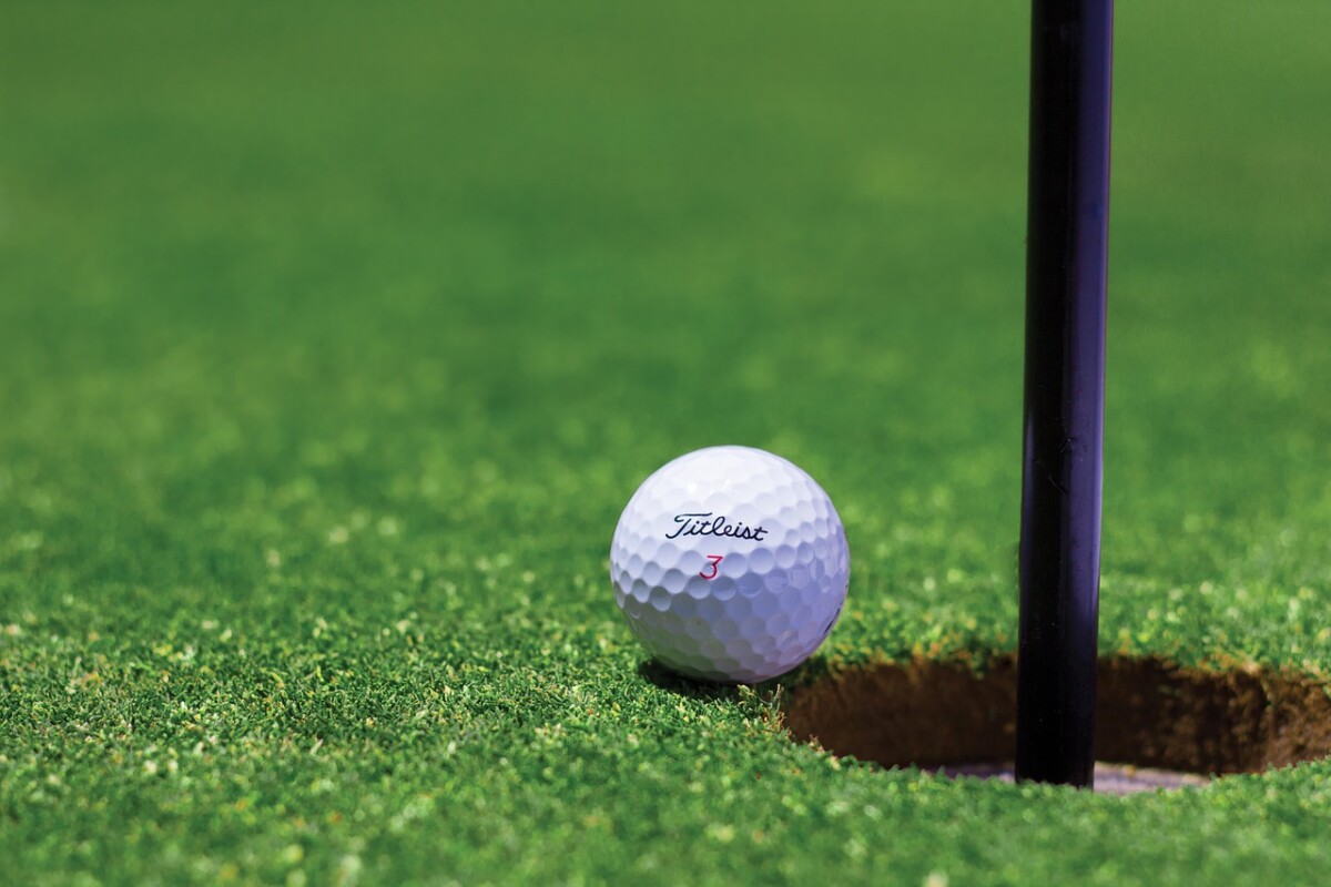 A golf ball by a hole on a course - pexels by Pixabay