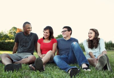 a group of 4 teenager sitting on the grass. Photo: Pexels.com