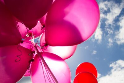 Pink and red balloons against a blue sky and clouds. Photo: Pexels