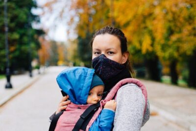 woman in facemask carrying baby. Photo: Pixabay